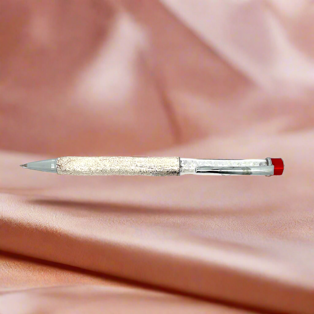 Decorative pen with glittery body and red cap on a pink fabric background